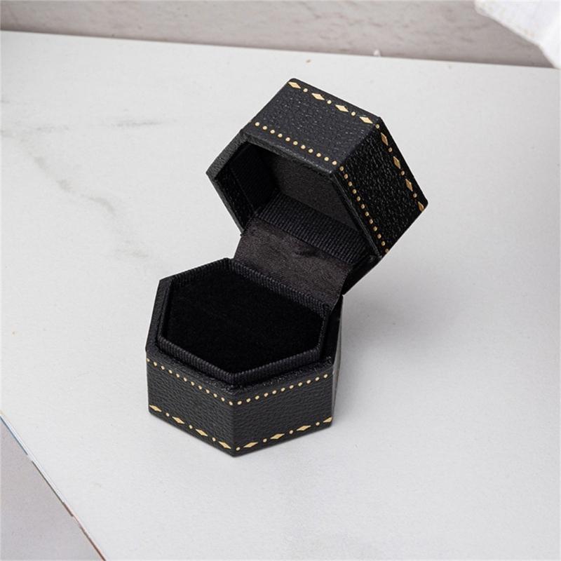 Hexagonal Ring Presentation Box with Black Interior, Gold-Tone Border Pattern, and Attached Lid for Retail Display