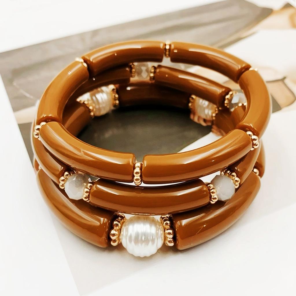 A set of three acrylic tubes connected by small golden flowers, adorned with crystal and faux pearl decorations, suitable for a lady's party.