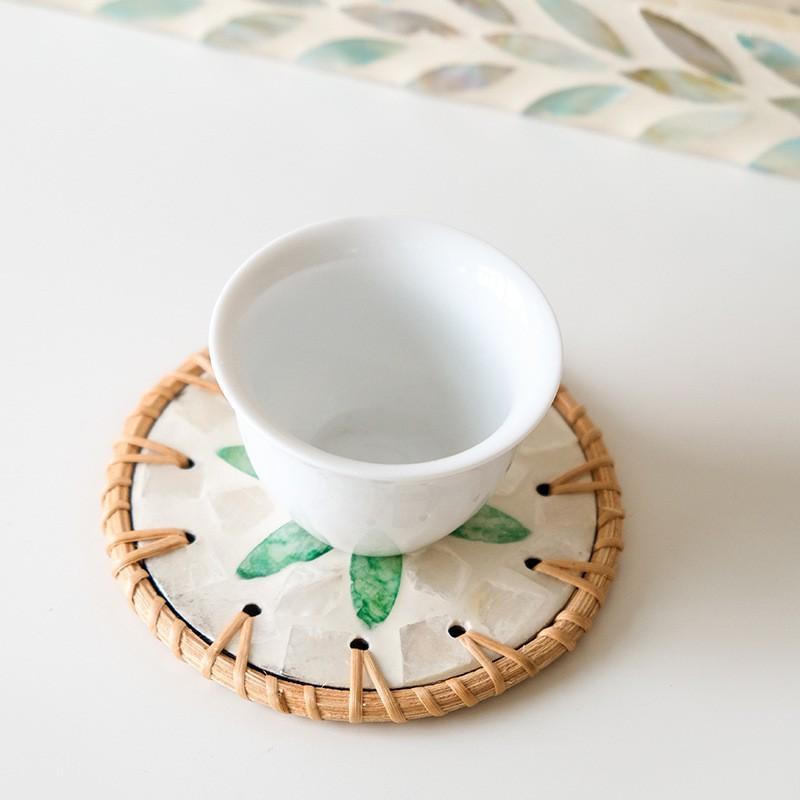 The hand - made rattan - edged shell coasters add a unique marine style to the tabletop.