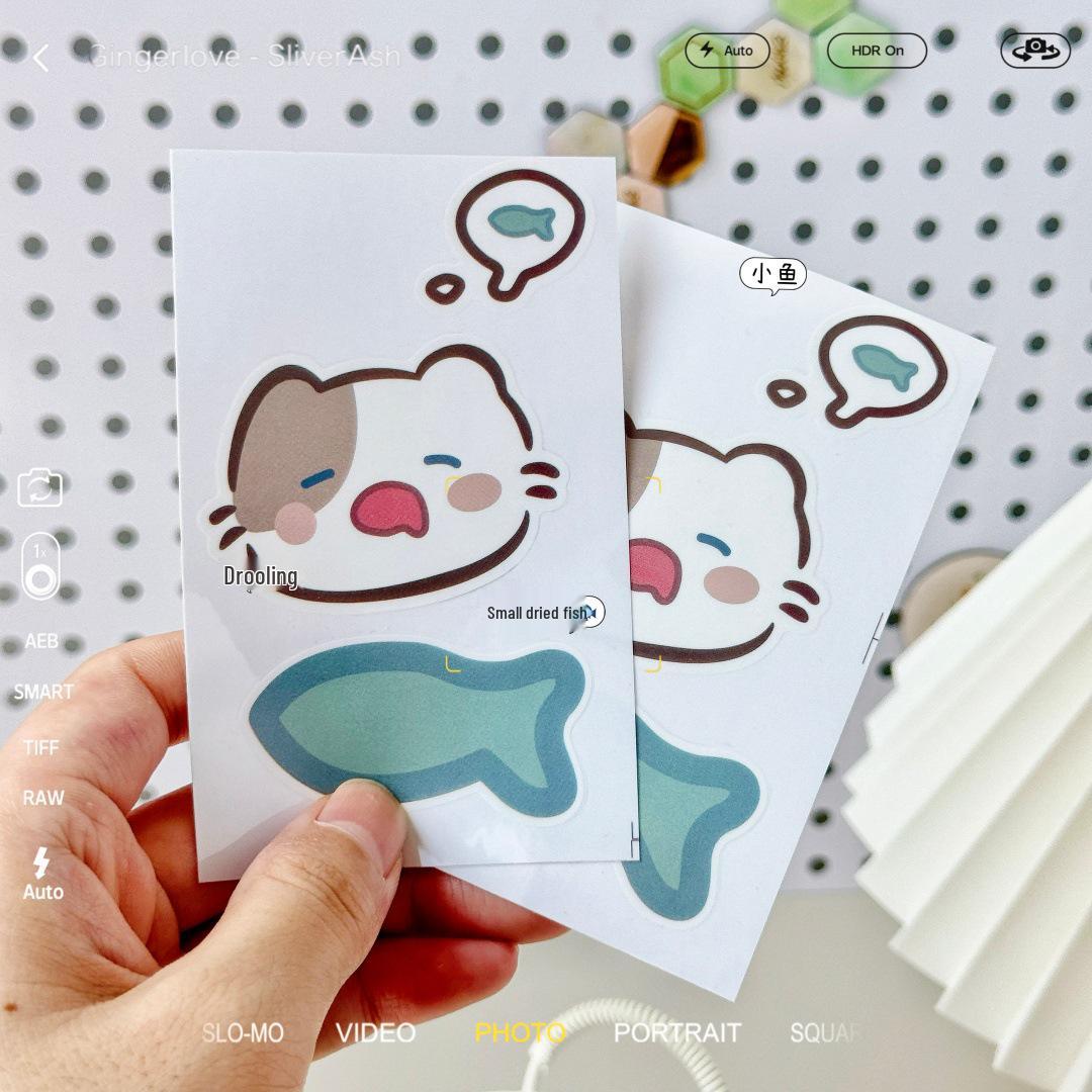 

Cartoon Kitten Eating Fish Sticker: Cute, Waterproof Transparent Decal for Bottles, Suitcases, or Computers.