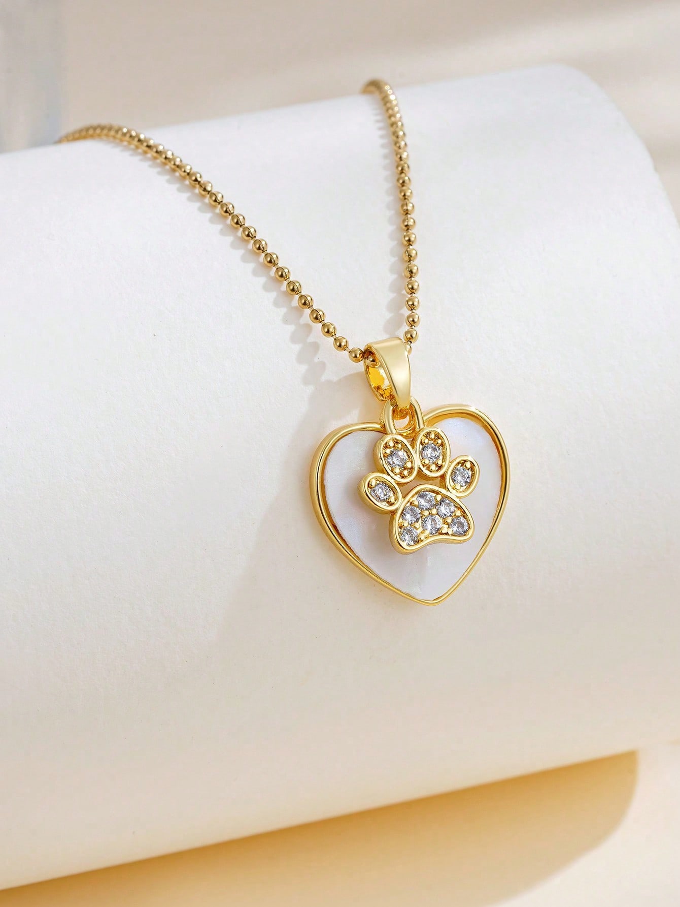 

1 gold plated stainless steel chain necklace with rhinestones, paw print and heart pendant. Unisex, one-size