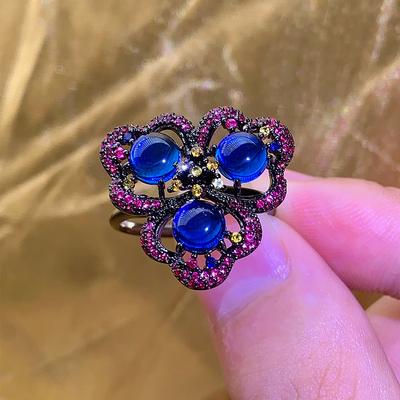 Schwarzgoldring, dunkle blumenförmige runde rote Korund-blaue Spinell-Ringöffnung