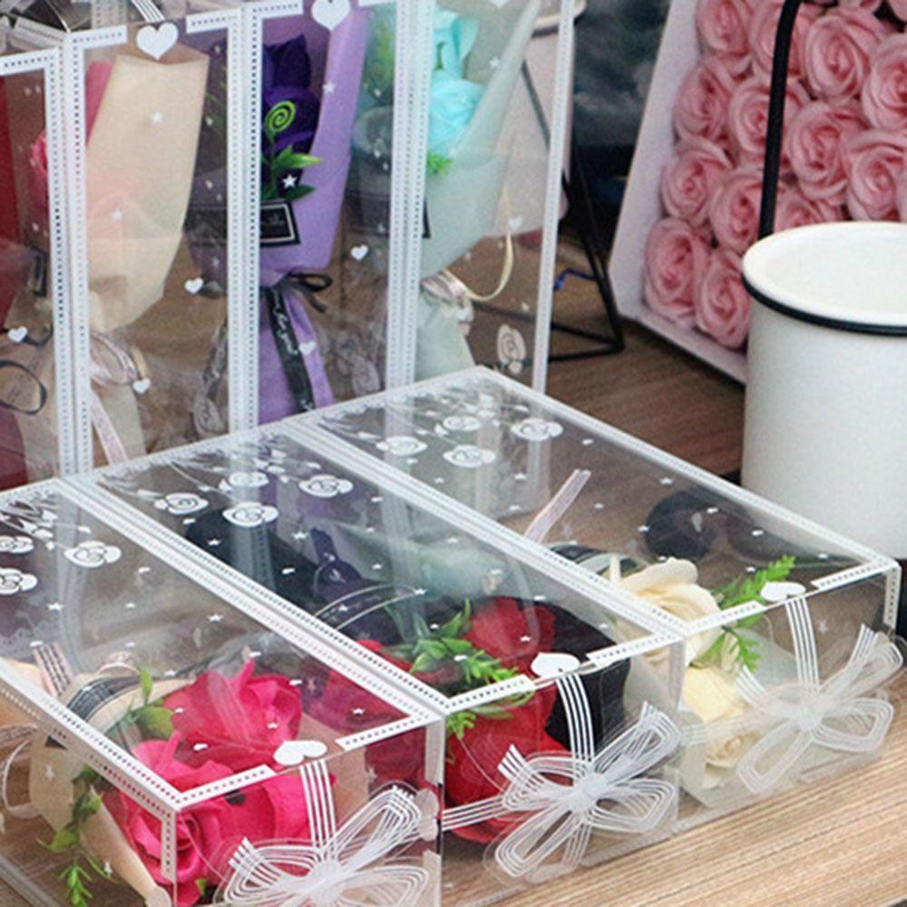 Rokā tur 3 mākslīgo rožu galvas ar kastīti mākslīgo ziedu modes rožu pušķis