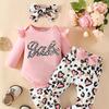 Kinderset bestaande uit een shirt met lange mouwen, camouflageprint met hartjesmotief, flared broek en hoofddoek, en een opdruk met letters.