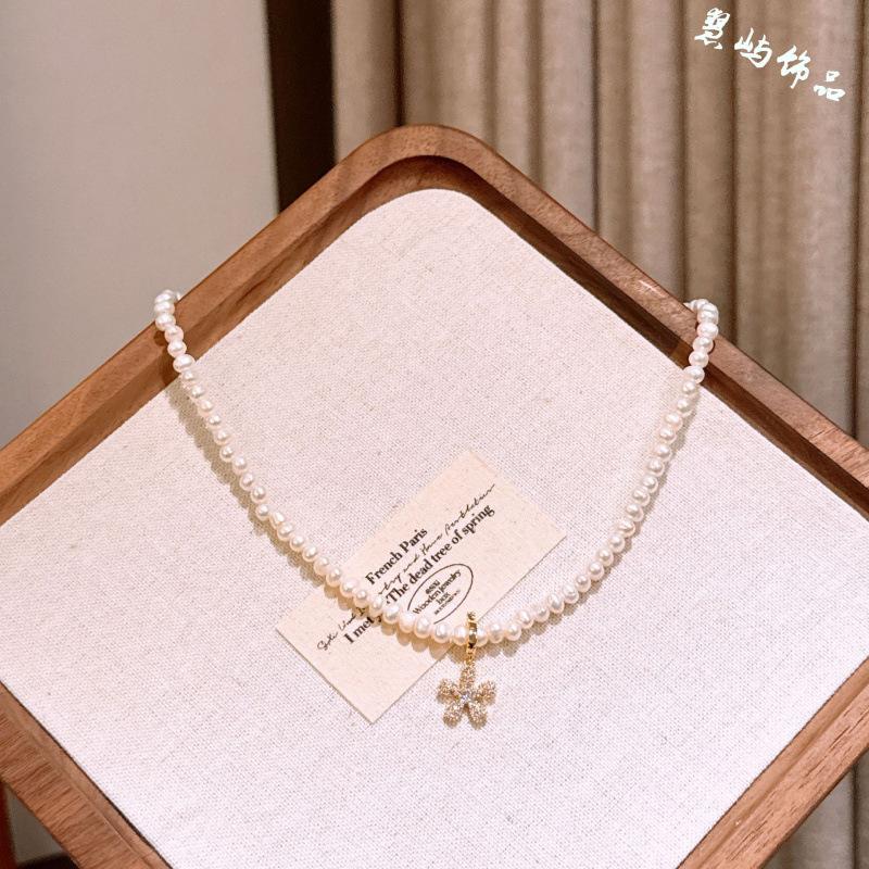 French-style delicate rice-shaped pearl necklace with detachable diamond-studded floral pendant, a niche and luxurious clavicle chain for women