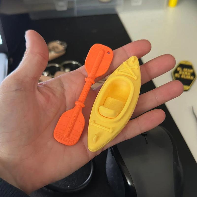 Mini breloczek do kluczy w kształcie kajaka z pasującym wiosłem i żywym wielokolorowym wzorem. Idealny dla miłośników kajakarstwa, dekoracja plecaka, mały prezent.