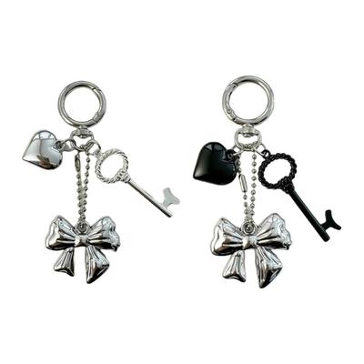 Modischer herzförmiger Schleifenanhänger. Anspruchsvoller Schlüsselanhänger mit Herzschleife. Charm-Accessoire für moderne Damenhandtaschen.