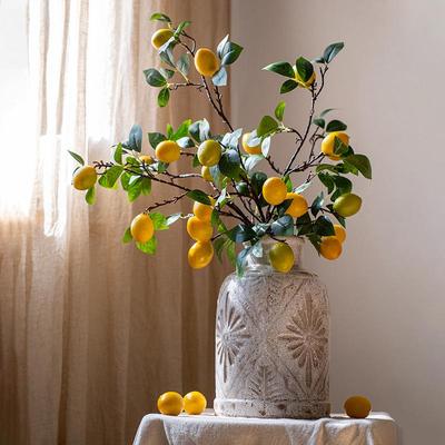 Wohnzimmer Bionische Blumenkunst: Dekoration mit künstlicher Blume an hohem Ast und Simulationszitronen-Arrangement