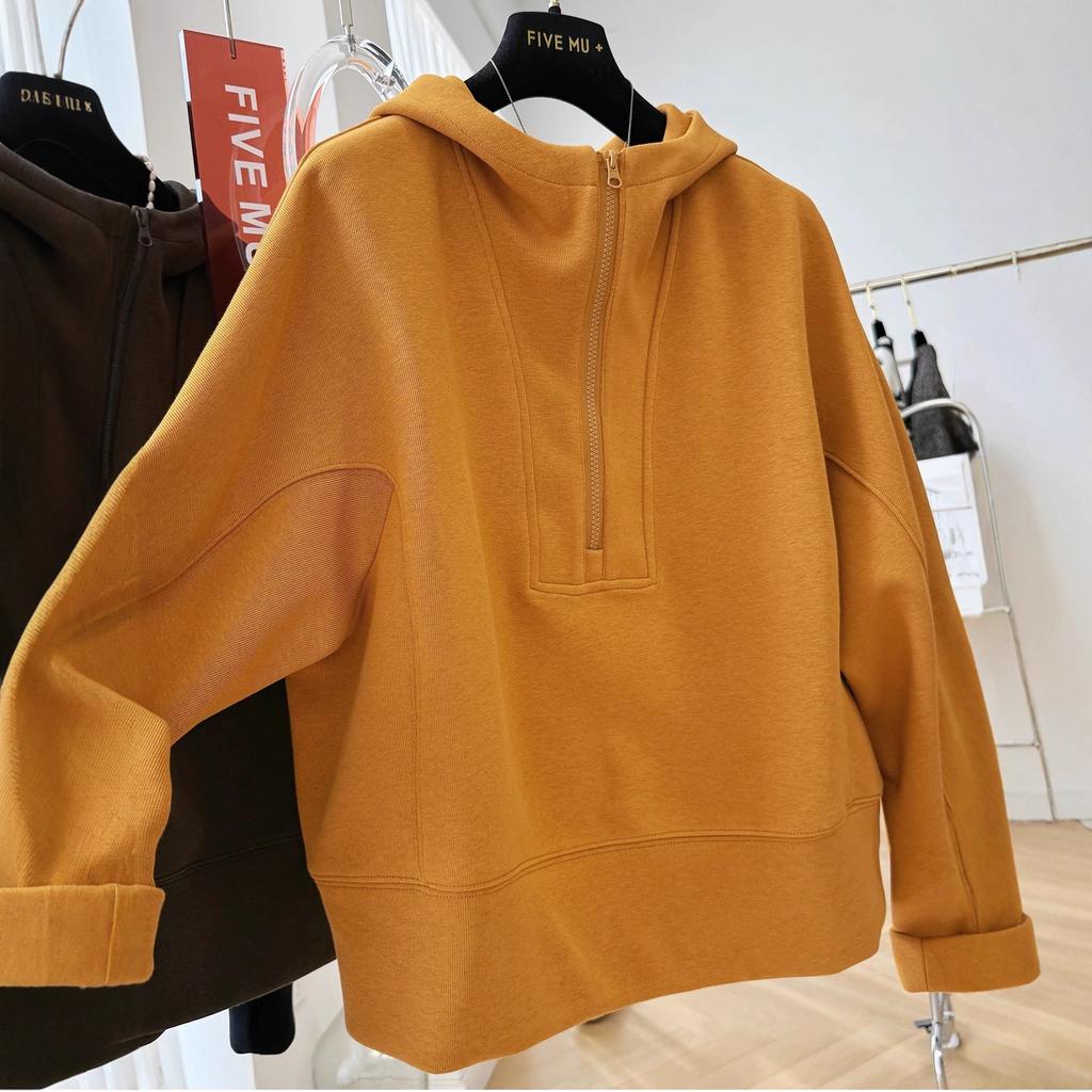 En lös, avslappnad och tillbakalutad huvförsedd tröja med halv dragkedja för kvinnor under hösten, som är extremt vacker