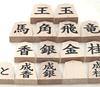 Wooden shogi pieces in regular script with a single maple character engraved on the back marked with black ink on the and presented in a paulownia