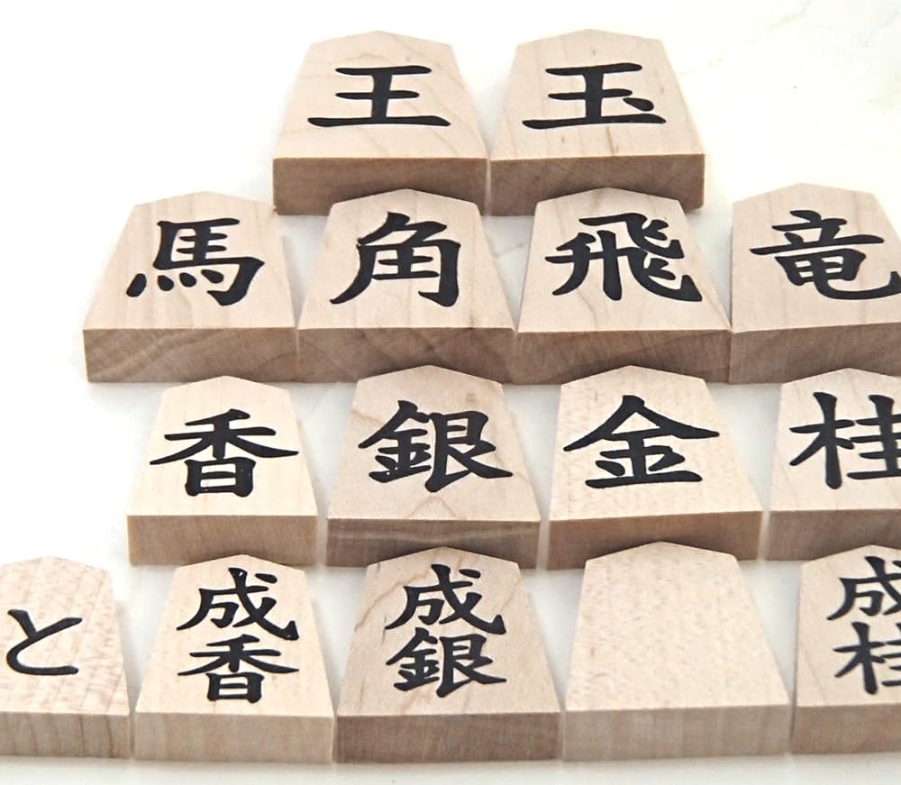 Wooden shogi pieces in regular script with a single maple character engraved on the back marked with black ink on the and presented in a paulownia