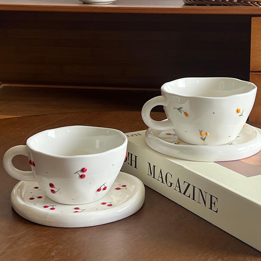 Ceramic coffee cup and saucer set, decorated with a small floral pattern.