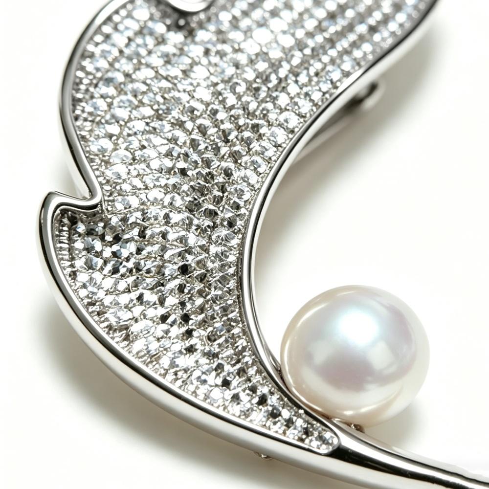 Elegant natural freshwater pearl brooch,with leaf shape, emitting natural luster. Made of copper with zircon accents.