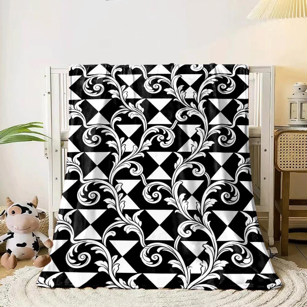 White ornate floral vines overlaying a black and white triangle grid. for all seasons blanket lunch break throw gift 80cm x 120cm