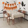 A vintage tablecloth with a Halloween theme, featuring ghosts and flowers.