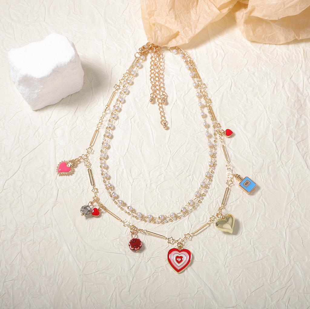 Koreanische Version von frischer und modischer Imitationsperlen-Dreischichtkette, gestapelte Halskette, öltropfenlegierter Liebesanhänger, Nischen-Damen