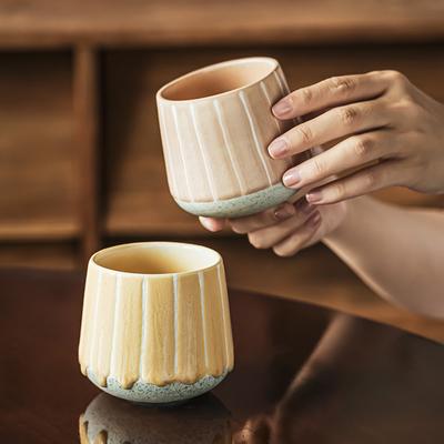 Eine Kaffeetasse, eine japanische Keramiktasse, eine kreative gestreifte Tasse, eine Haushalts-Teetasse, eine Tasse ohne Henkel und eine Suppen-Trinktasse halten.