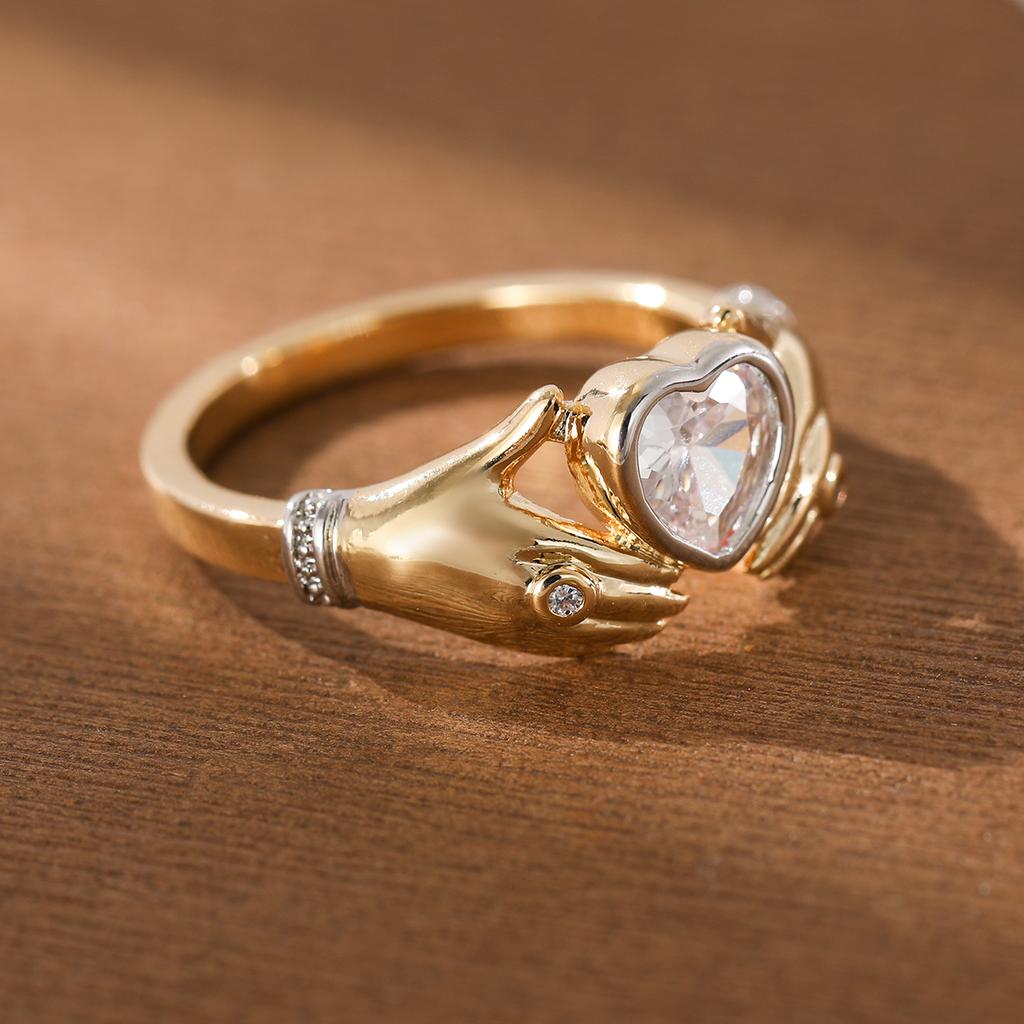 Luxurious hands holding a heart-shaped synthetic gemstone ring made of copper. Women's jewelry ring for a banquet.