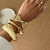 Pulsera de moda con textura metálica lisa y diseño geométrico en forma de cruz.