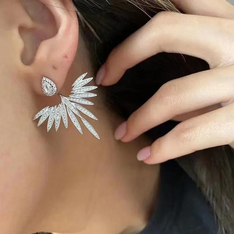 The design features a two-part structure: a pear-shaped crystal stud at the front, paired with a dramatic, symmetrical wing-like United States