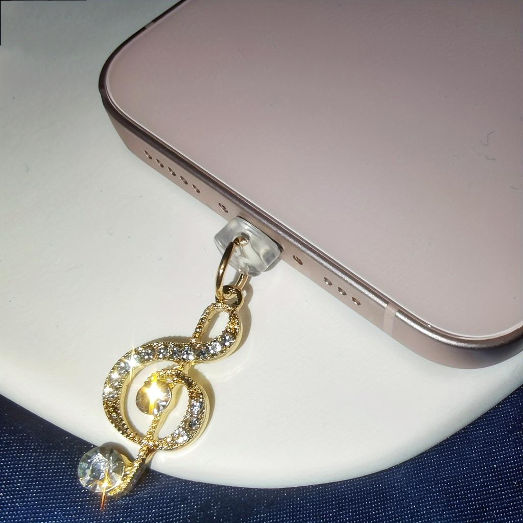 Chraňte svůj telefon stylovou zlatou prachovou zátkou ve tvaru hudební noty, ozdobte svůj telefon závěsným popruhem.