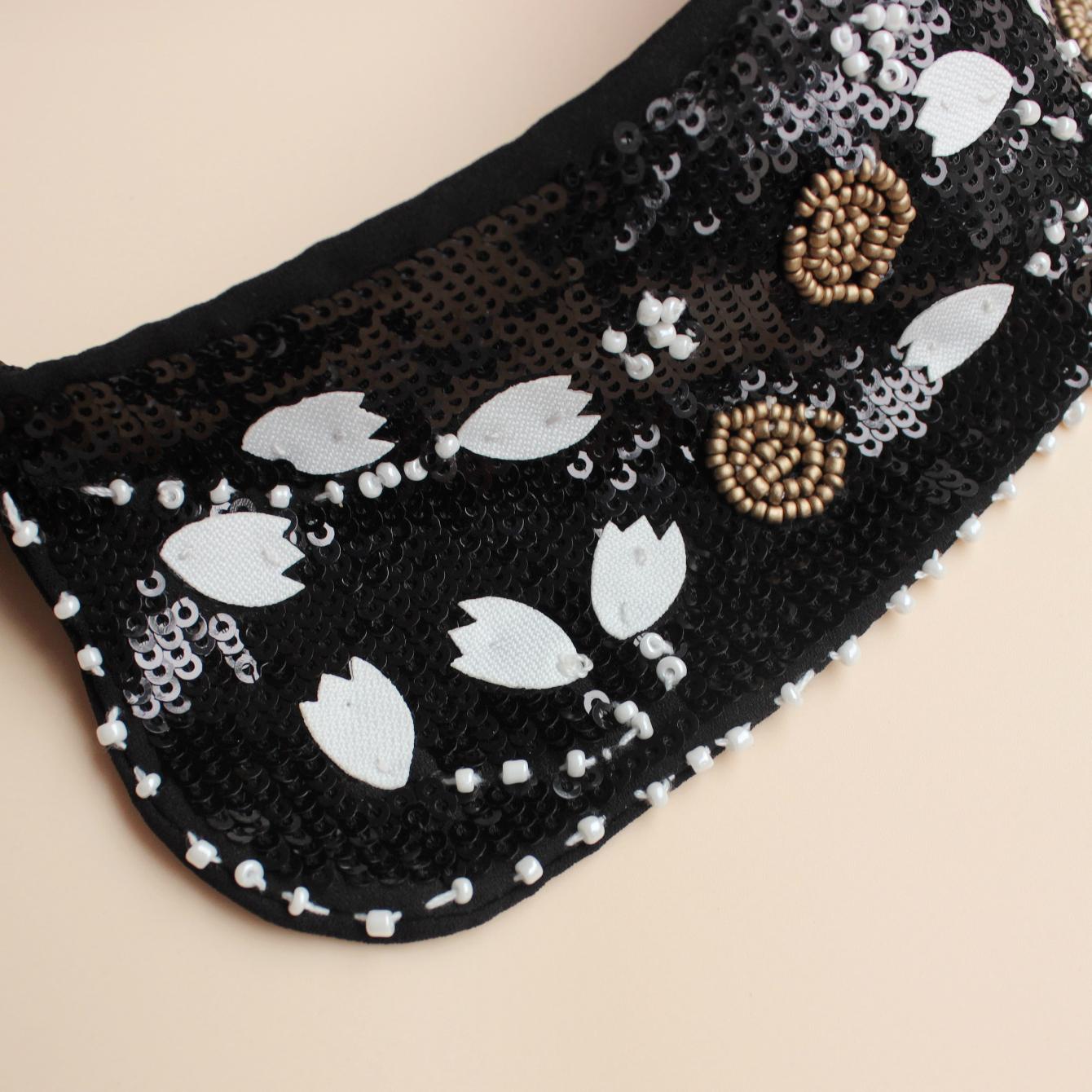 

Модный аксессуар, роскошный воротник с пайетками. Классический черный фон с белыми цветами. Инкрустировано блестящими бусинами-орнаментами