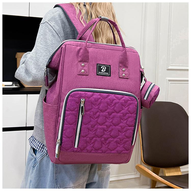 New style mommy bag with large capacity, featuring a patchwork design, contrasting colors, and a versatile, fashionable look. It’s a waterproof