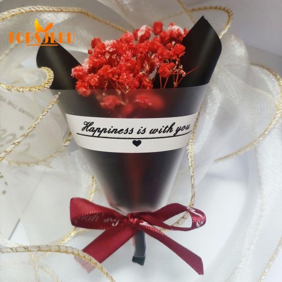 In Papier eingewickelte, mit getrockneten Blumen duftende Schleierkrautblüten, Schleife mit Buchstabenmuster, langanhaltende, lebendige Farbe, Blumenstrauß als Geschenk zum Valentinstag