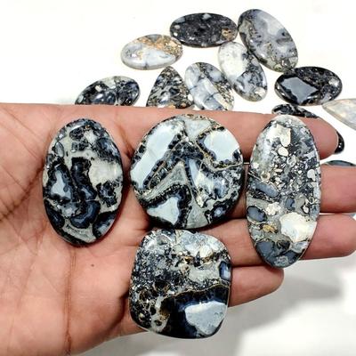 Lote de pedras preciosas soltas cabochão maligano preto com diferentes formatos e tamanhos, usadas para fazer joias.