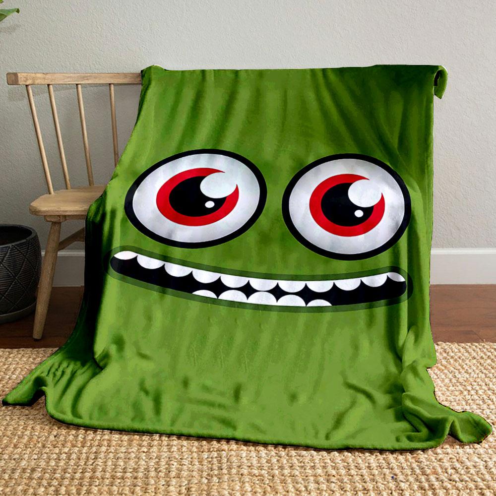 A green face with large red eyes and a wide, toothy grin. for all seasons blanket lunch break throw gift