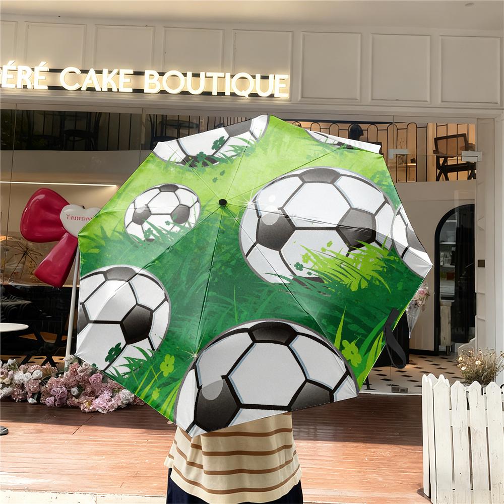 A Football-themed Folding Umbrella - Featuring a Vibrant Green Grass Design with Multiple Black and White Soccer Ball Patterns