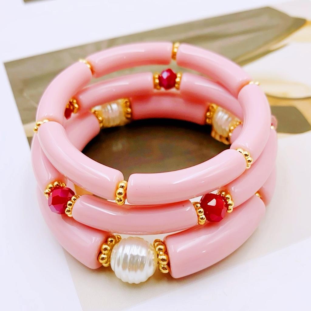 A set of three acrylic tubes connected by small golden flowers, adorned with crystal and faux pearl decorations, suitable for a lady's party.