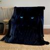 A sleek black panther with glowing blue eyes in a dark background. for all seasons blanket lunch break throw gift