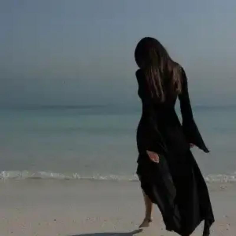 Abito lungo da donna bianco con scollo a V profondo, laccetti sul davanti, volant e maniche lunghe, ideale come copricostume da spiaggia.