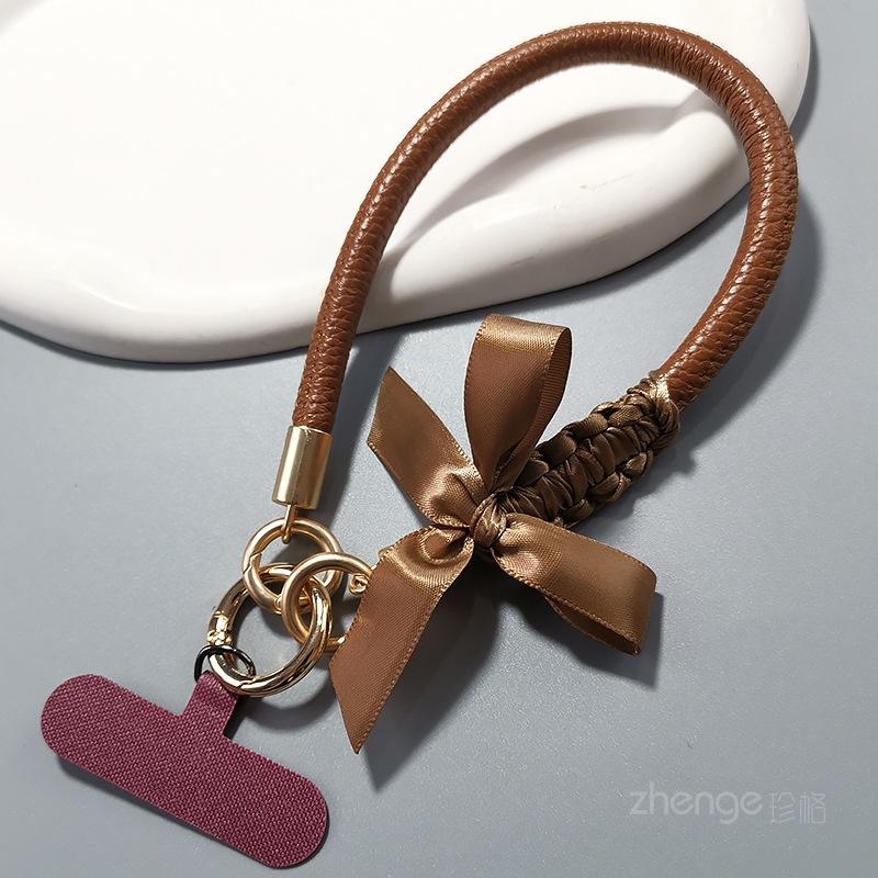 

Bow leather mobile phone lanyard women s ins fashion small fragrance style hand-held wrist rope mobile phone case hanging rope short model [coffee bow] gold leather wrist strap