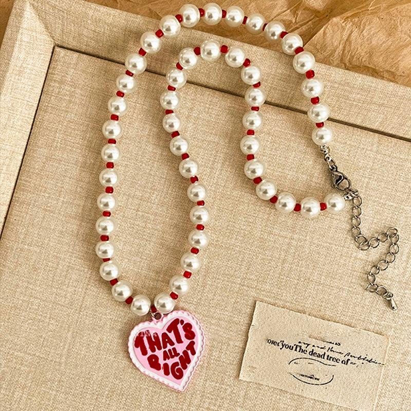 

Розовое эмалированное колье-подвеска в виде сердца с буквенным принтом, подходящее для женщин и девушек, с красными бусинами из искусственного жемчуга и металлическим чокером.