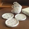 Ceramic coffee cup and saucer set, decorated with a small floral pattern.