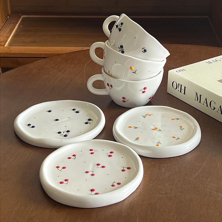Ceramic coffee cup and saucer set, decorated with a small floral pattern.