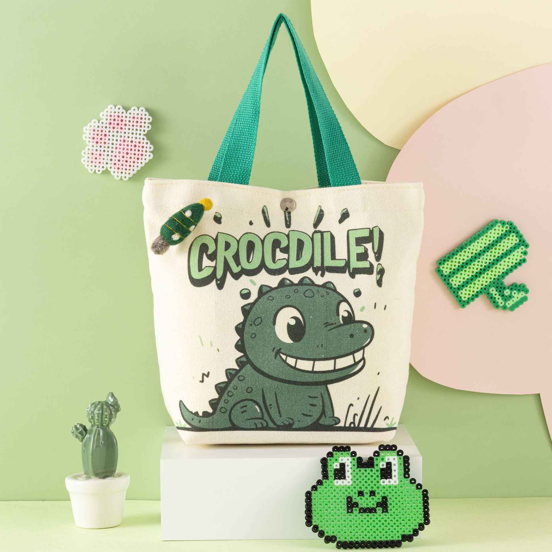 

Сумка из холщовой ткани с изображением мультяшного динозавра-крокодила — вместительный детский подарок для повседневного использования. 27x22x10 cm