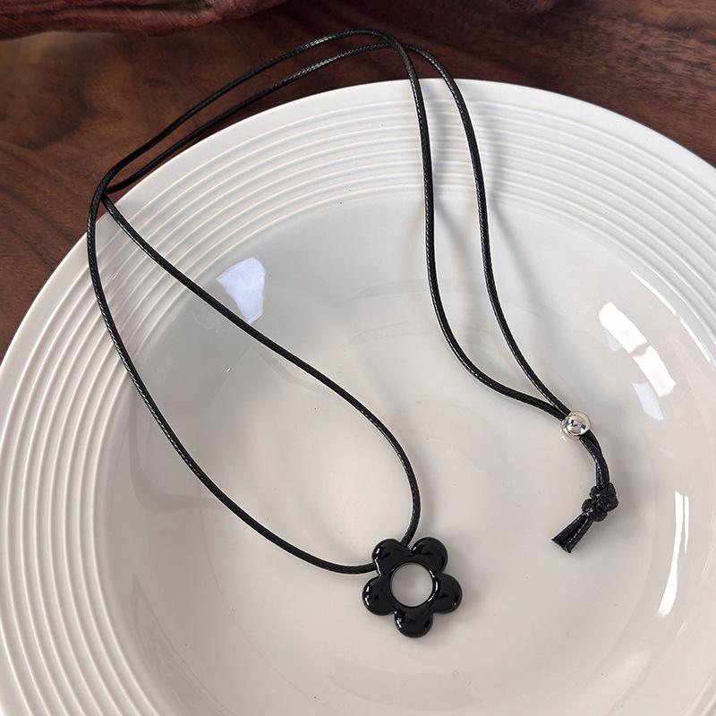 

A pendant necklace. Hollow resin flower pendant necklace with adjustable knot for everyday wear. Black