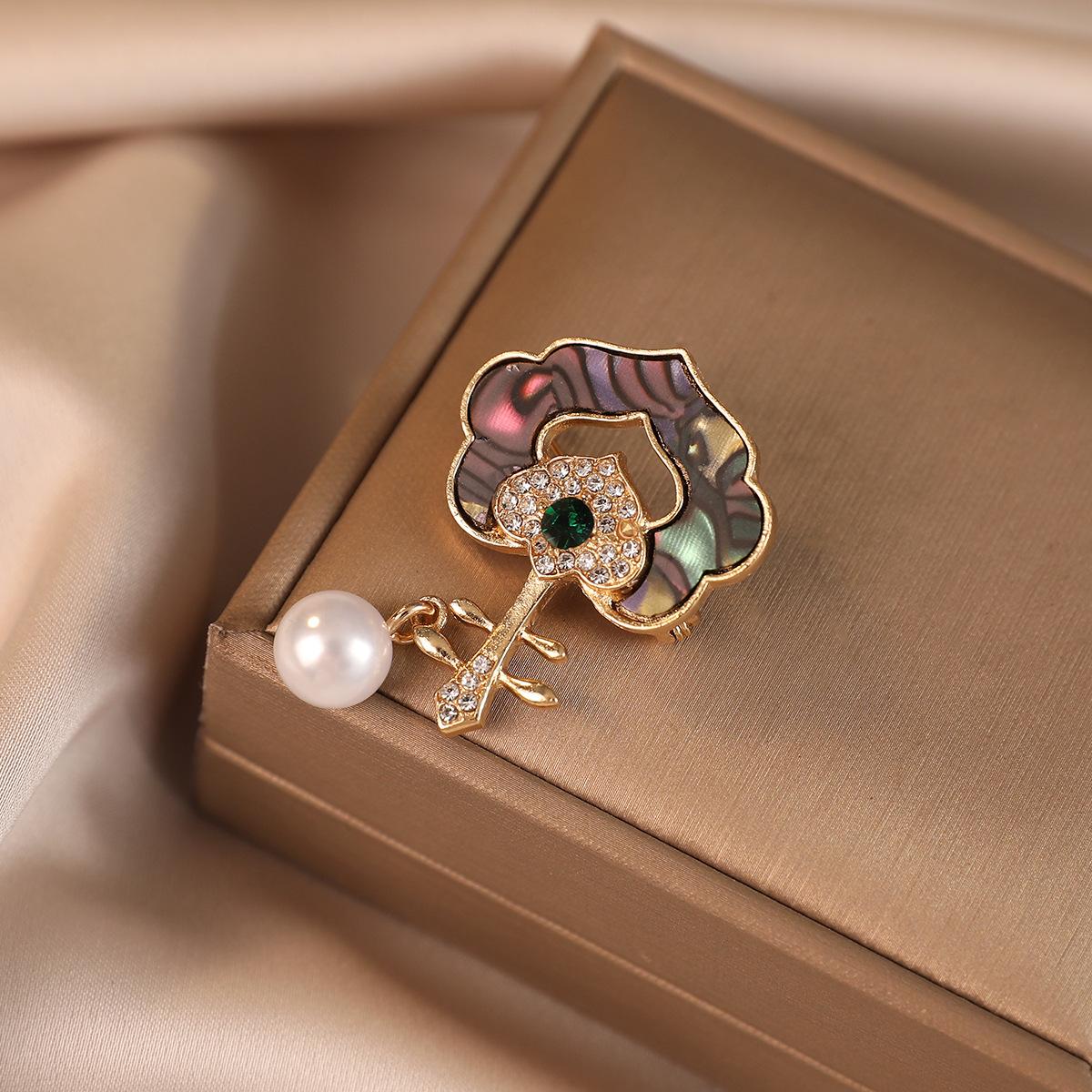 

Elegant Key Shaped Brooch with Inlaid Shell Pattern and Crystal Accents Featuring a Single Faux Pearl Pendant Suitable for Various Accessories