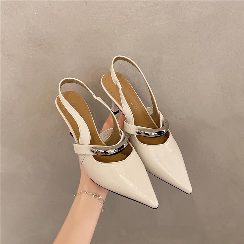 A Woman Wearing Half-slippers with An Inwardly Raised Metal Buckle Toe Cap and A Genuine Leather Pointed Toe on The Outside