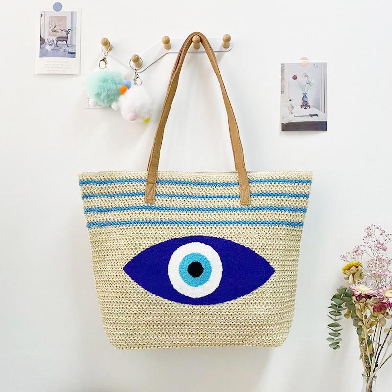 Umweltfreundliche Stroh-Schultertasche mit blauem Augen-Stickdesign für Sommerausflüge