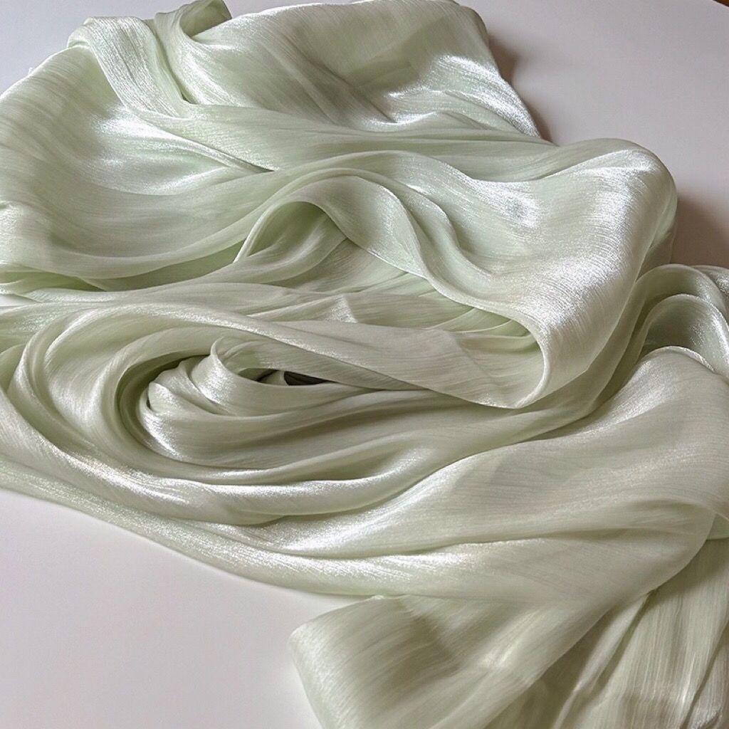 Soft shiny creased organza fabric with a smooth texture suitable for wedding dresses formal gowns and designer clothing fabrics