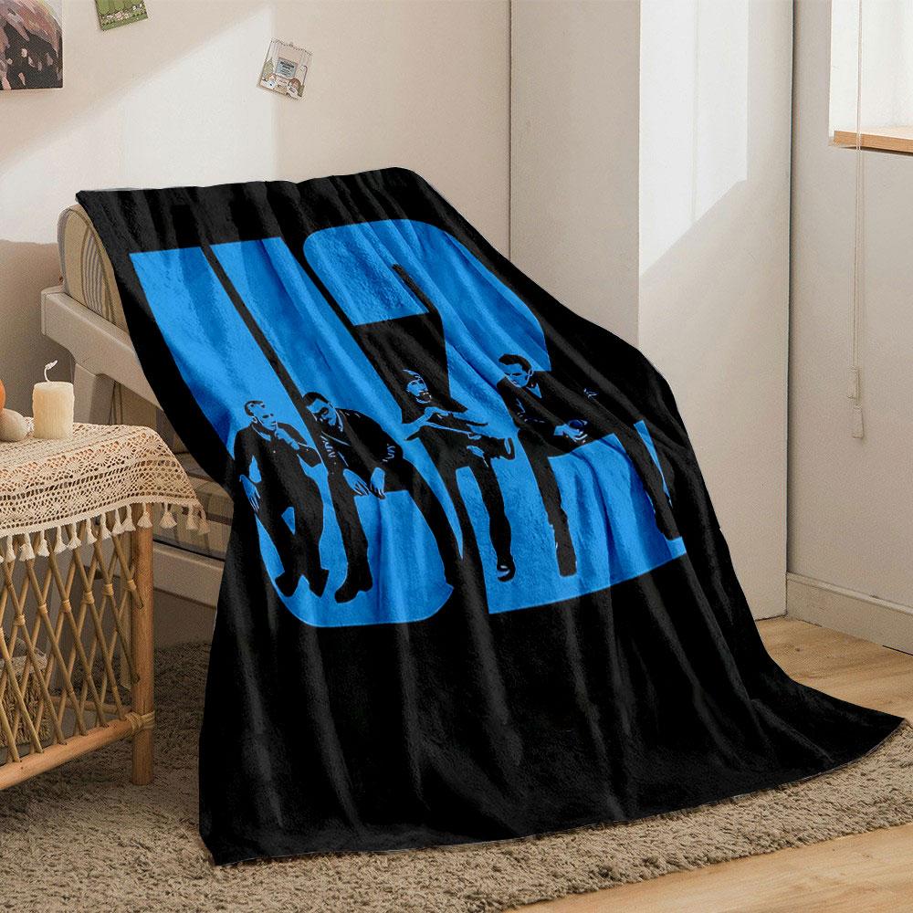 Bold blue "U2" text integrates silhouettes of seated figures in black. for all seasons blanket lunch break throw gift