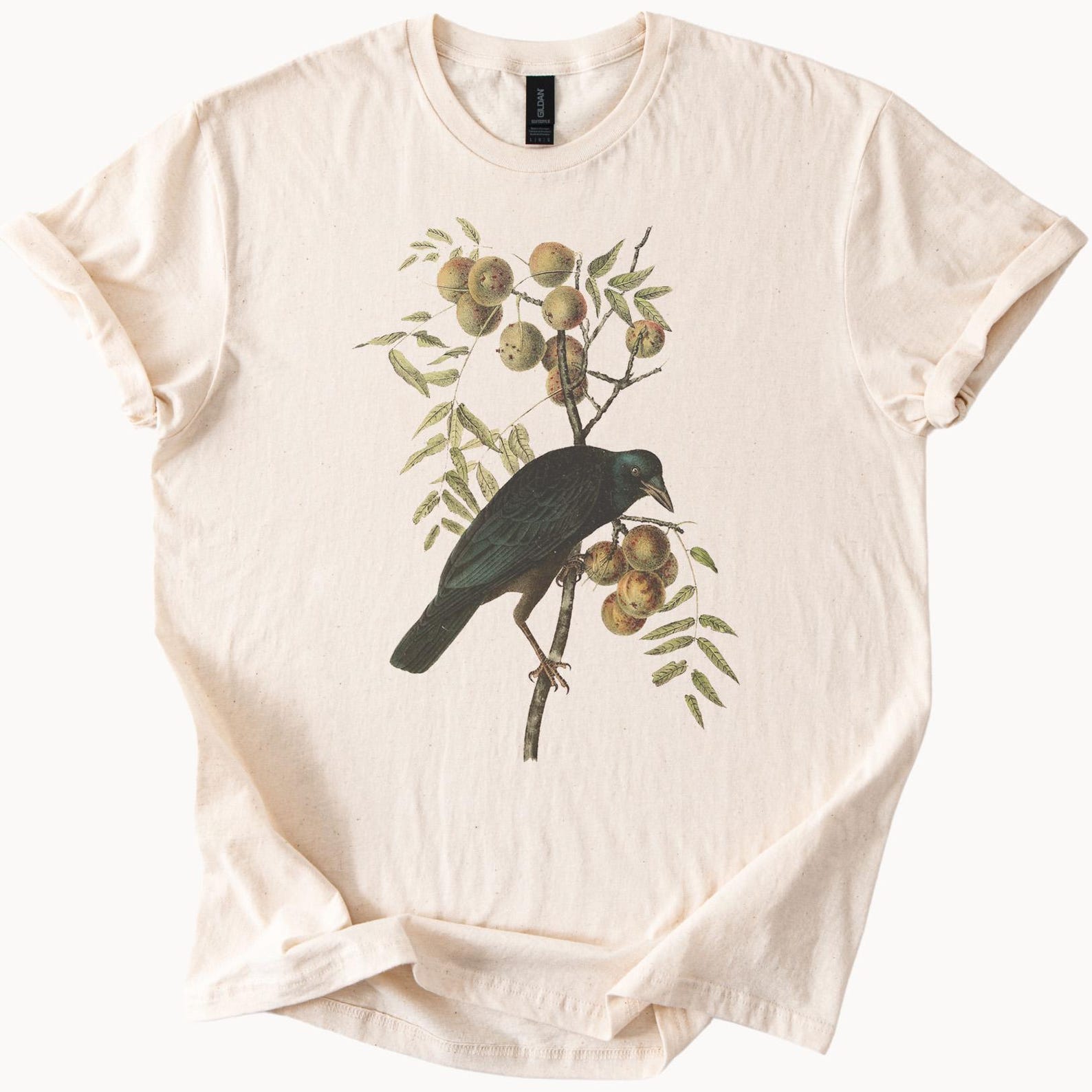 Black bird perched on fruit tree graphic t shirt nature inspired animal art unique illustration peach blossom design casual outfit tee 140