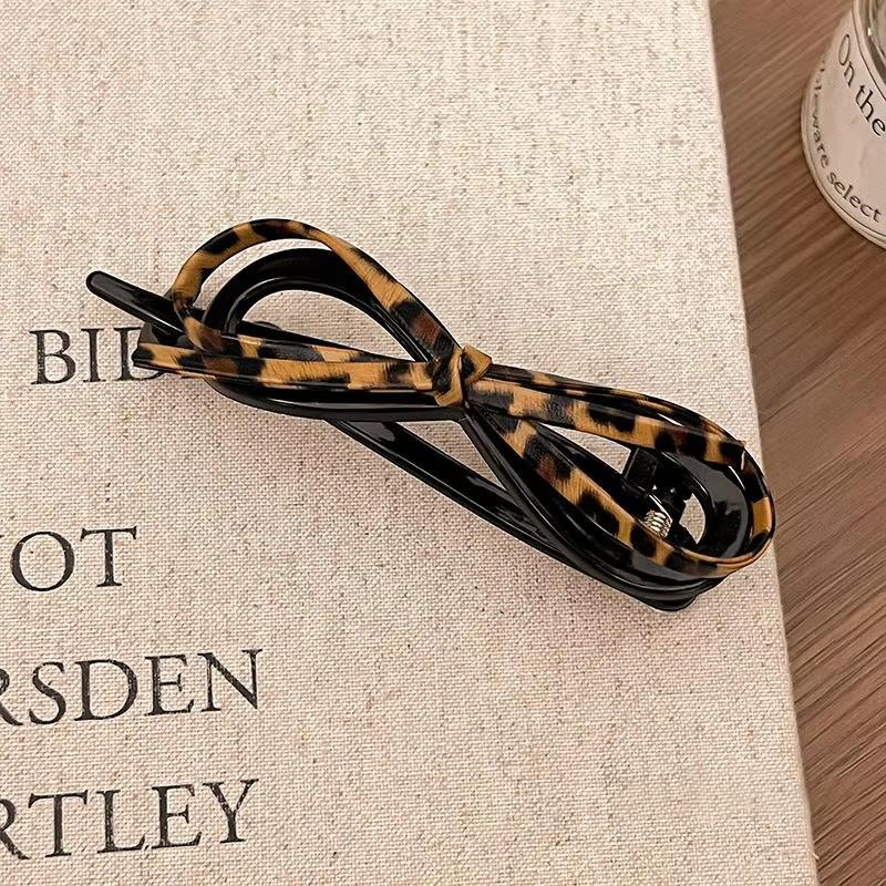 A Fashionable and Sweet Leopard Print Updo Headpiece with a Leather Bow Twist Clip On the Back of a Woman's Head