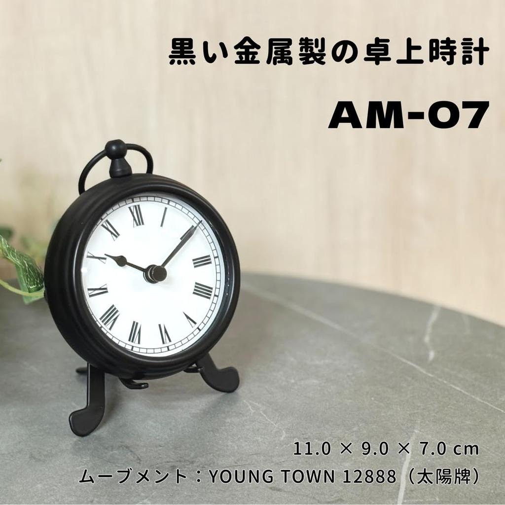 The BESTIME AM-07 is a small, exquisitely crafted black metal desk clock with a white dial and easy-to-read black numerals. It measures 14.9cm high,