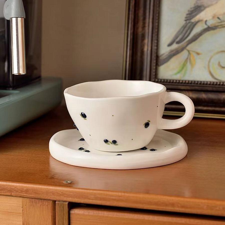Ceramic coffee cup and saucer set, decorated with a small floral pattern.