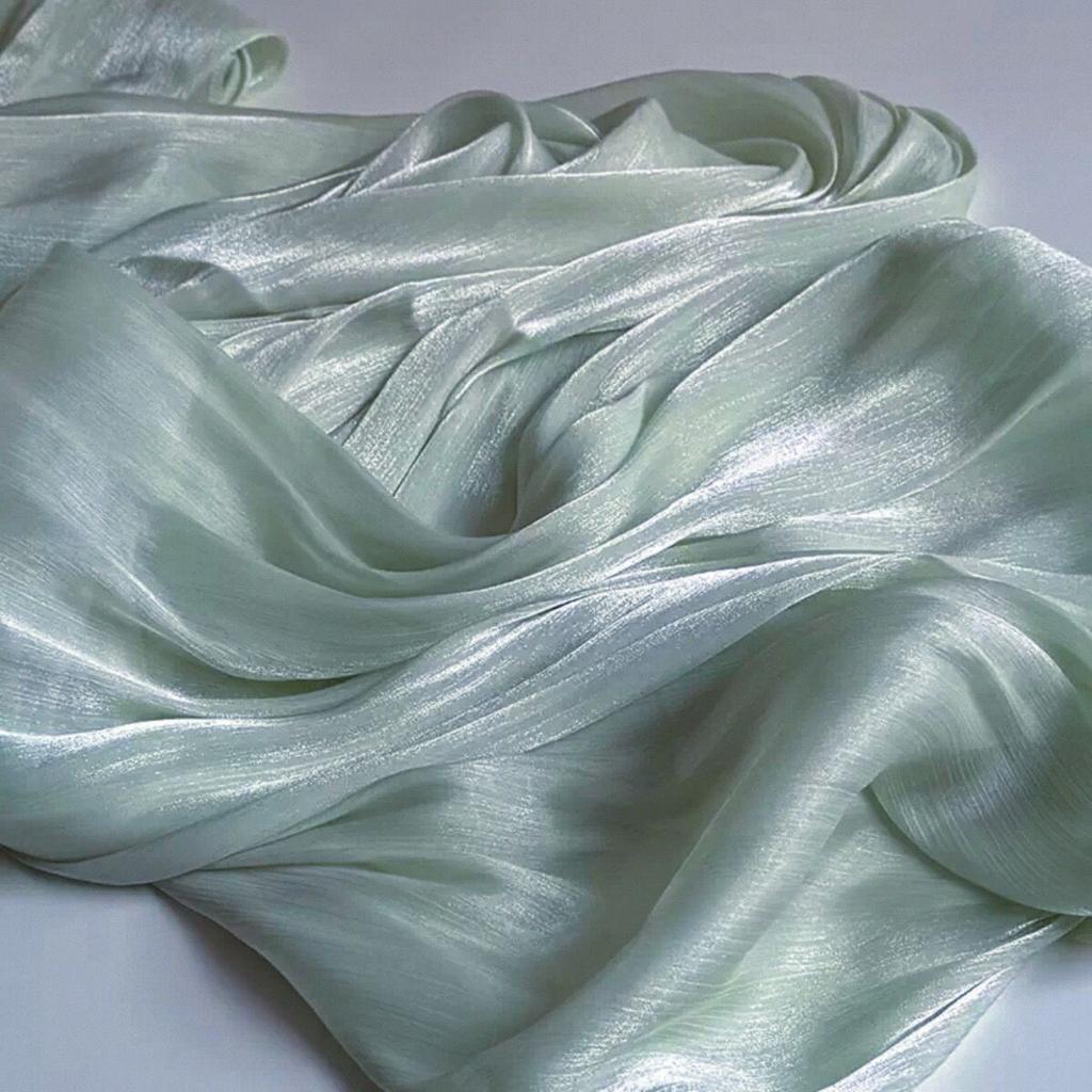 Soft shiny creased organza fabric with a smooth texture suitable for wedding dresses formal gowns and designer clothing fabrics